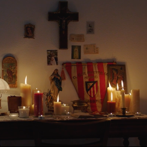 A wide view of a personal shrine featuring candles, religious imagery, and an Atlético de Madrid banner.