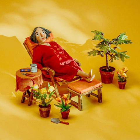 Stop-motion clay character resting outside a tent, surrounded by camping items in a stylised outdoor setup.