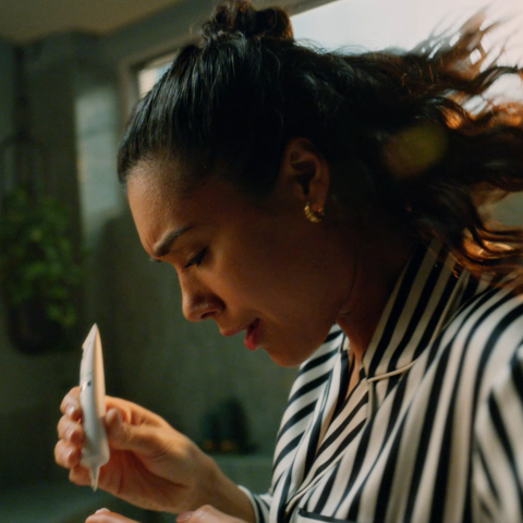 Close-up of woman applying facial serum during evening skincare routine.