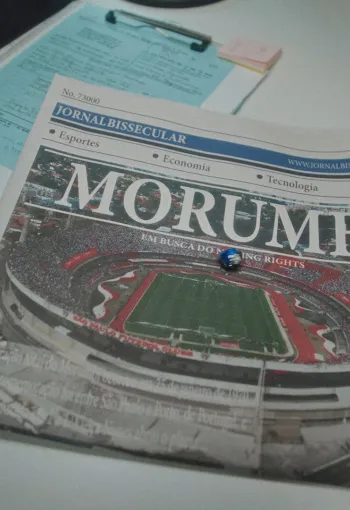 Newspaper with a main story image of a football pitch, the paper is next to a packet of biscuits.